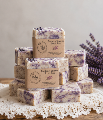 A stack of handmade lavender scrub soap bars wrapped in kraft paper labels, displayed on a lace doily with dried lavender sprigs in the background.